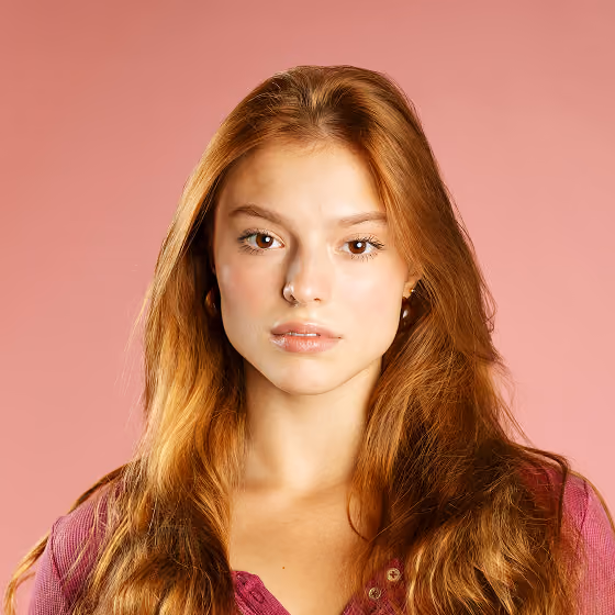 Young woman with long red hair and neutral expression against a pink background.